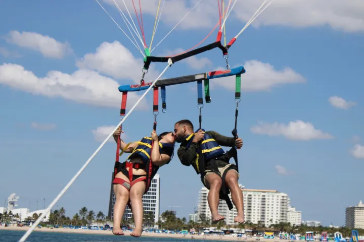 a group of people flying kites in a body of water