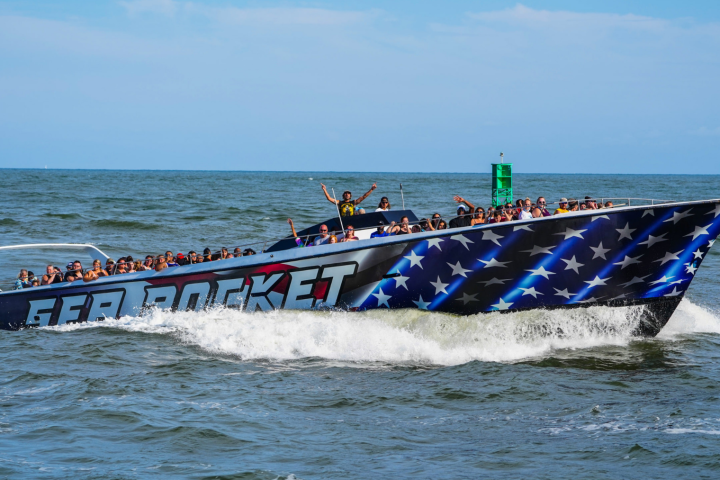 Speedboat with American flag design and passengers cruising on the ocean.
