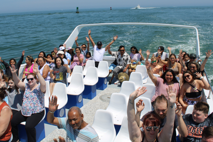 Group of people raising hands on a boat in the ocean.