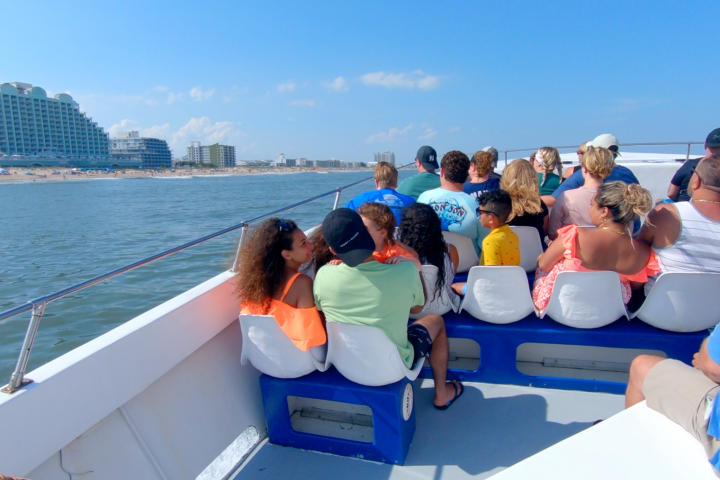 People sitting on a boat looking towards a beach and buildings.