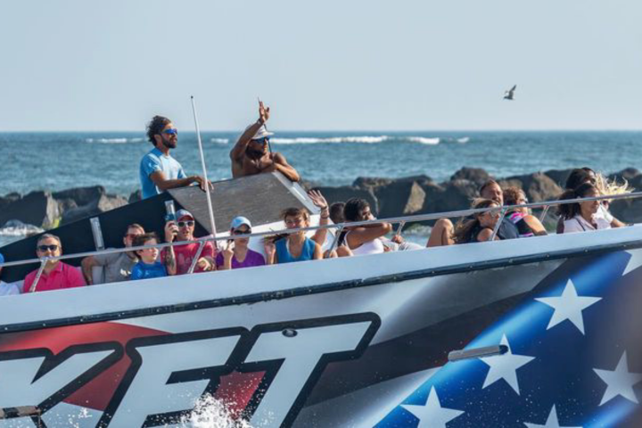 People enjoying a ride on a speedboat near rocky shoreline.