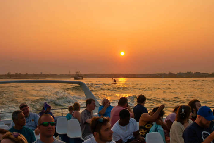 People on a boat with sunset over the water in the background.