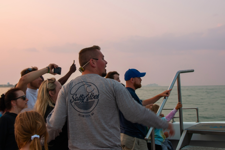 Group of people on a boat gazing at the sea during sunset.