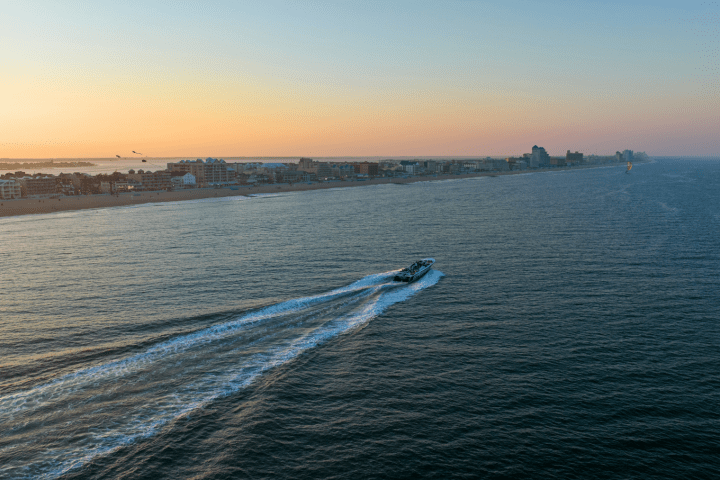 Boat sailing near a coastline at sunset.