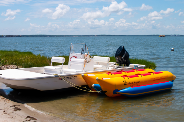 Small motorboat and inflatable banana boat on a calm lake shore.