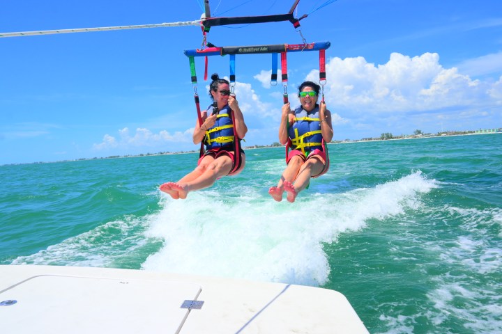 Two people parasailing over the ocean on a sunny day.