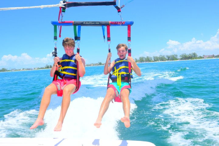 Two people parasailing over the ocean on a clear, sunny day.