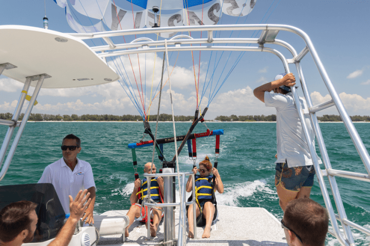 People on a boat preparing for parasailing with blue ocean and clear sky.