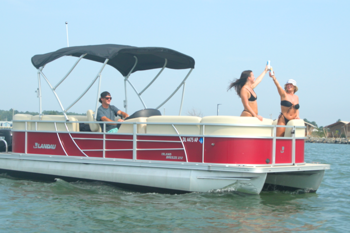 People enjoying a boat ride on a red pontoon boat on a sunny day.