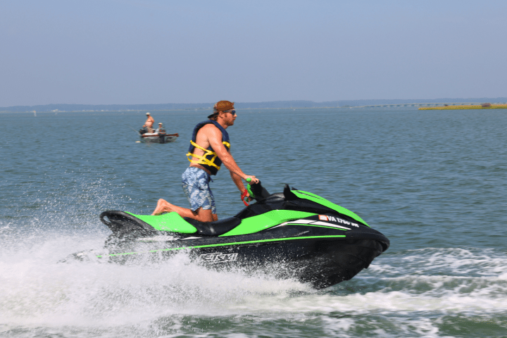 Person riding a green and black jet ski on open water.