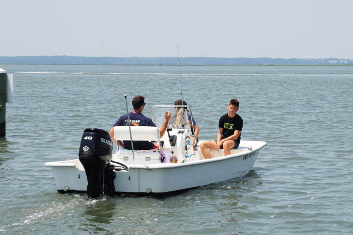 Three people in a small motorboat on a calm lake with distant shoreline.