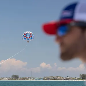 a man flying a kite in the blue water