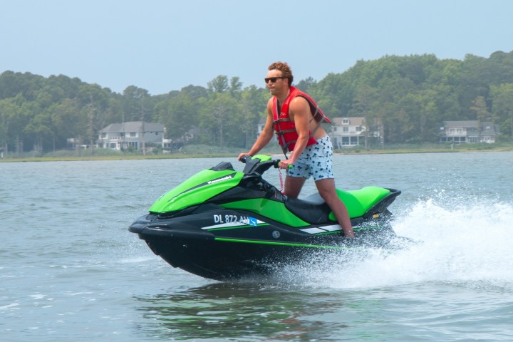 a man riding on the back of a boat in the water