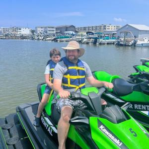 a person riding a motorcycle with a boat in the water