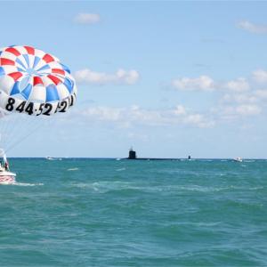 a group of people flying kites in a body of water