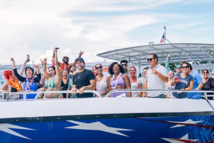 Group of people celebrating and posing on a boat with star pattern, holding drinks and smiling.