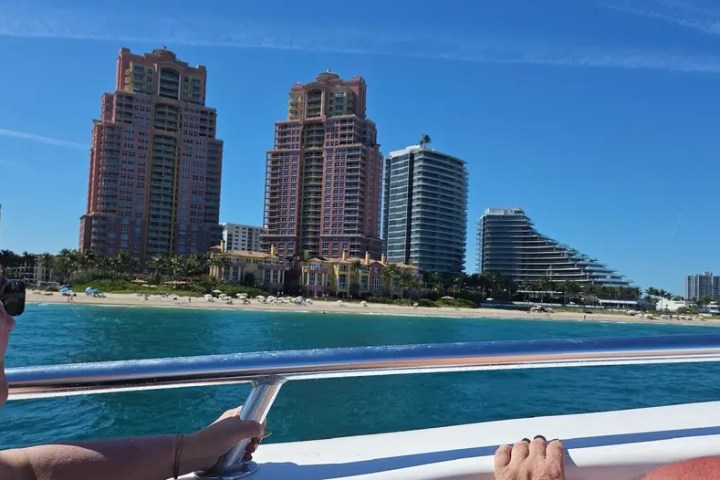 Person on boat with view of coastal high-rise buildings against a blue sky.