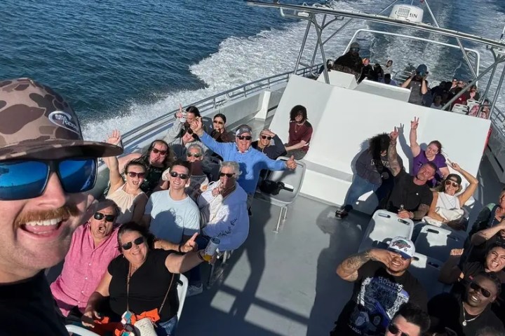Group of people taking a selfie on a boat with the ocean in the background.