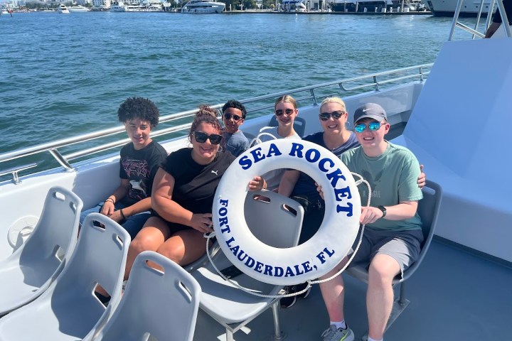 Group of people on a boat holding a 'Sea Rocket' lifebuoy in Fort Lauderdale, FL.