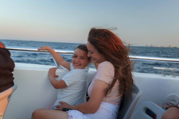 People smiling on a boat with ocean and skyline in the background.