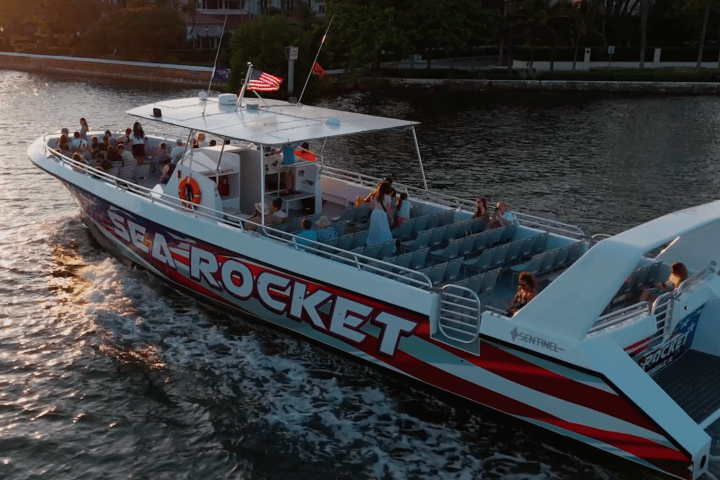 A tour boat named Sea Rocket with passengers cruising on a calm waterway at sunset.