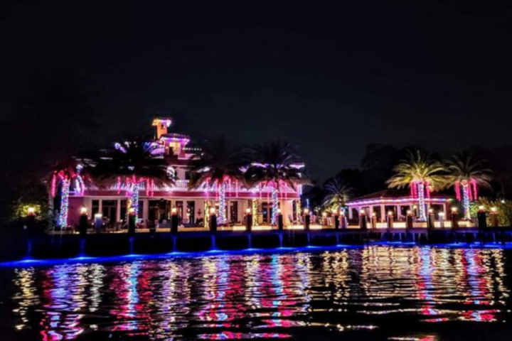 House with colorful lights reflecting on water at night.
