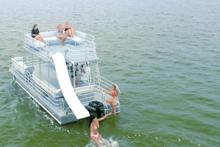 Four people on a boat with a slide in a lake.