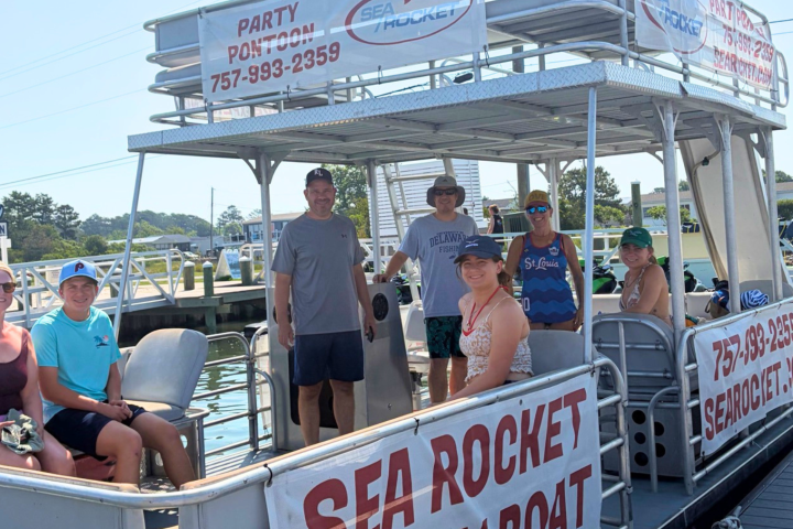 Group of people on a docked party boat with 'SEA ROCKET' signs.