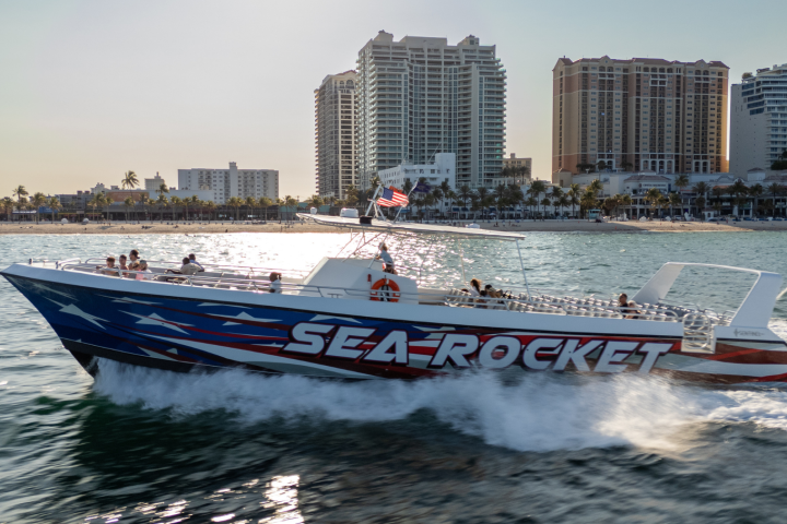 Speedboat named Sea Rocket on water near a city skyline.