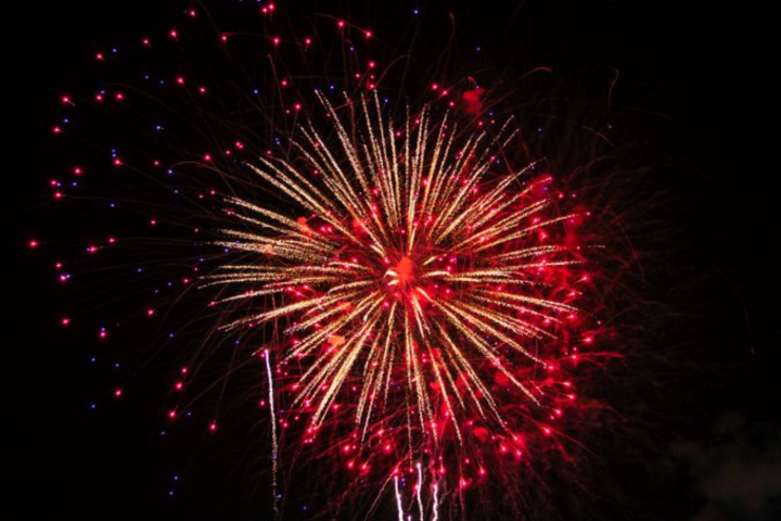 Red fireworks burst against a black sky, with small blue and white accents.