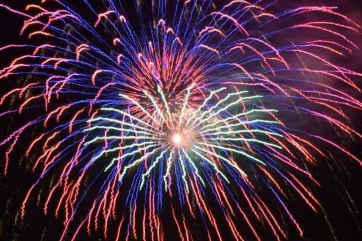 Colorful fireworks burst with red, blue, and green trails in a dark sky.