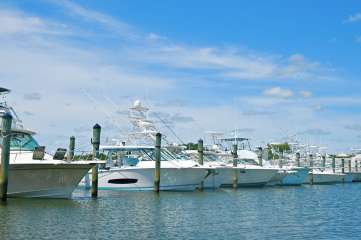 White boats docked in marina under blue sky with clouds.