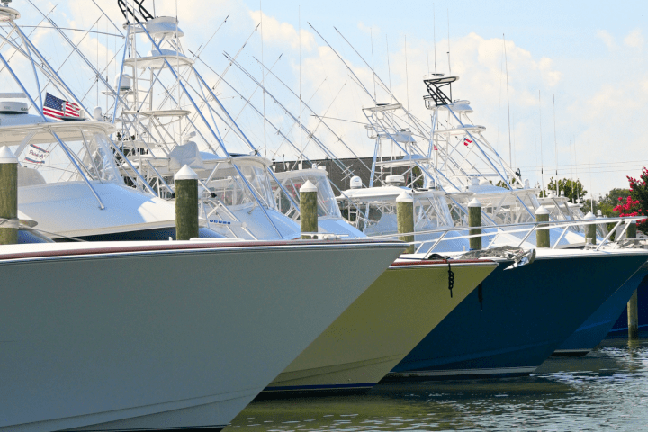 Row of docked fishing boats with tall antennas in a marina.
