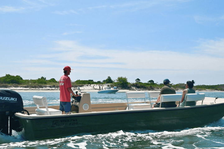 Three people on a motorboat with a Yamaha engine on a sunny day.
