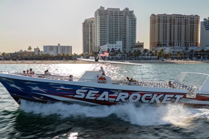 Speedboat named 'Sea Rocket' with American flag design near city shorelines.