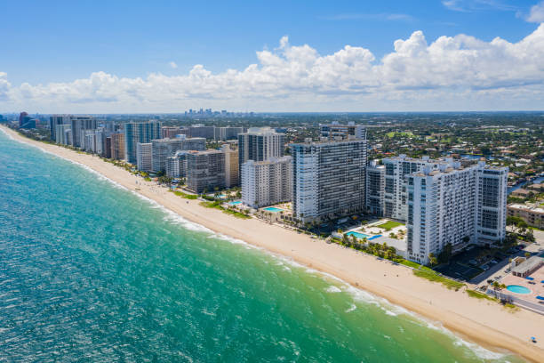 Aerial view of a beach lined with tall buildings and a cityscape in the background.