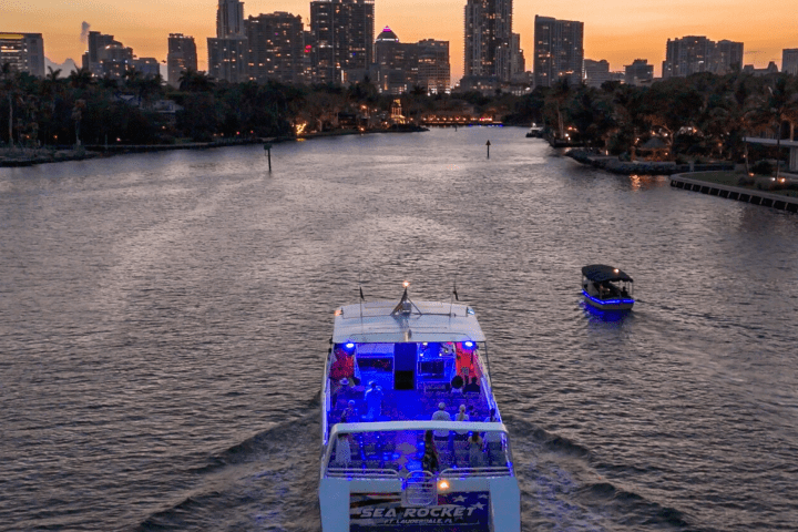 Boats on a river at dusk with city skyline in the background.