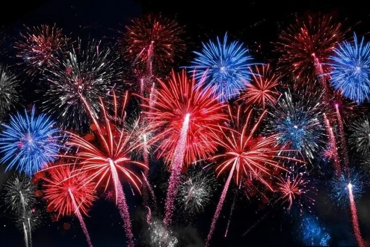 Vibrant red and blue fireworks bursting in a night sky.