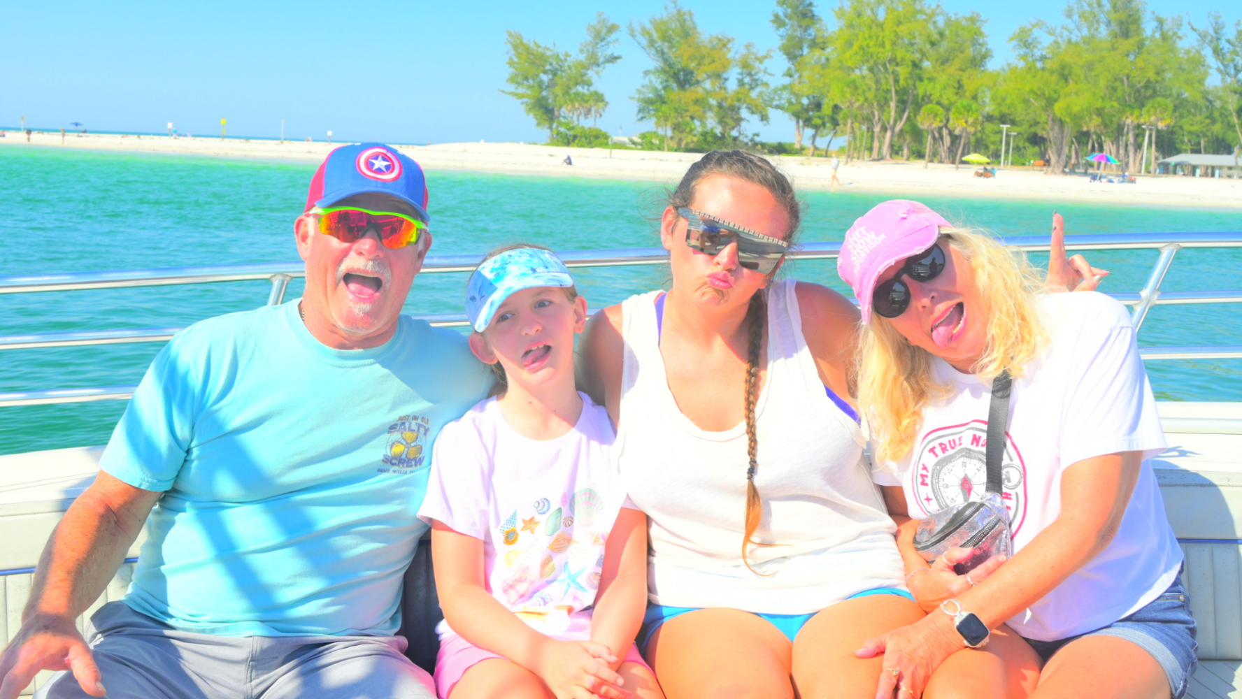 A family enjoying a fun moment together on a private boat cruise near Bradenton Beach with clear turquoise water in the background.