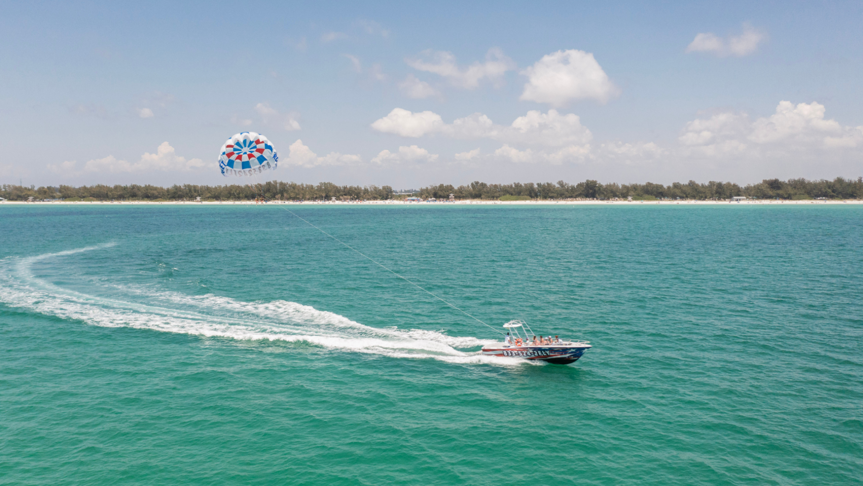 Parasail boat cruising near Bradenton Beach with a parasail chute soaring high above the Gulf of Mexico.