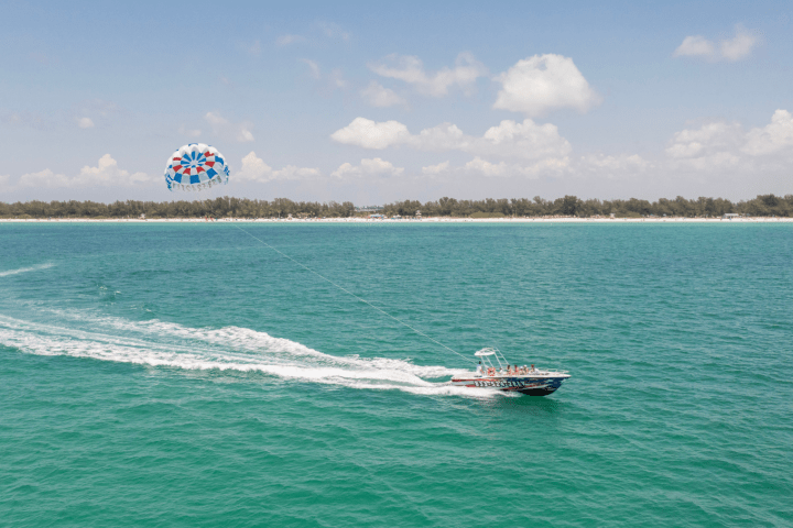 Parasail boat cruising near Bradenton Beach with a parasail chute soaring high above the Gulf of Mexico.