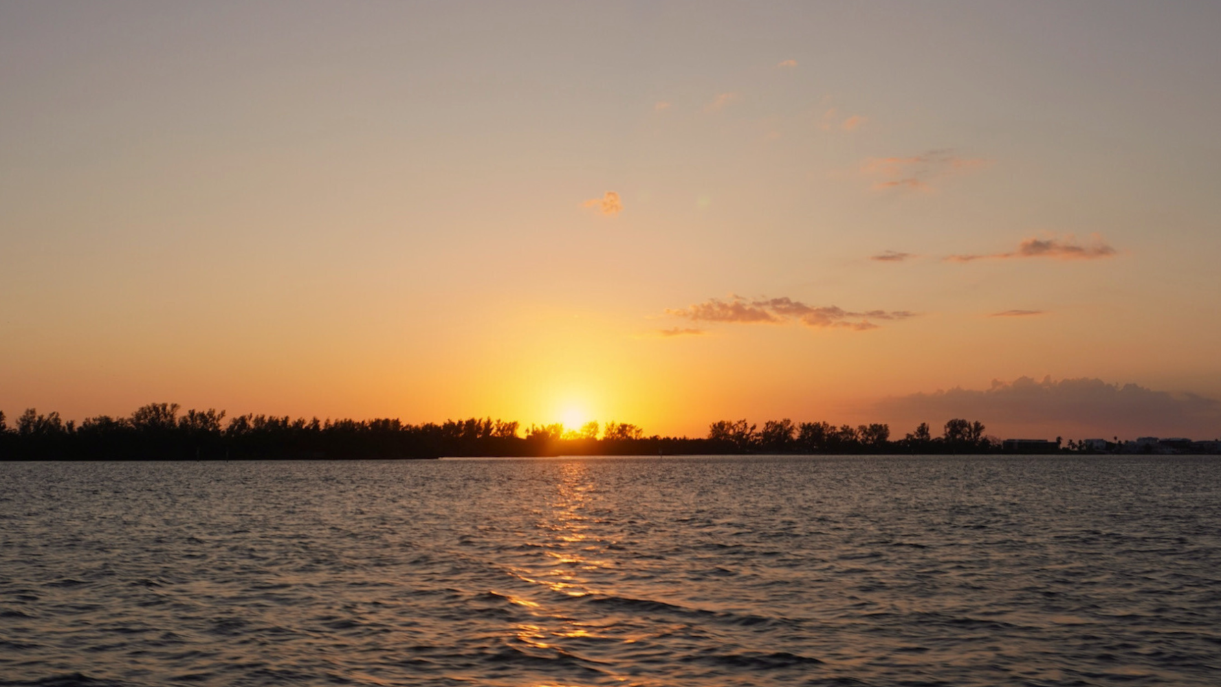 Vibrant Gulf Coast sunset viewed from a private boat near Bradenton Beach, with warm colors reflecting off the water.