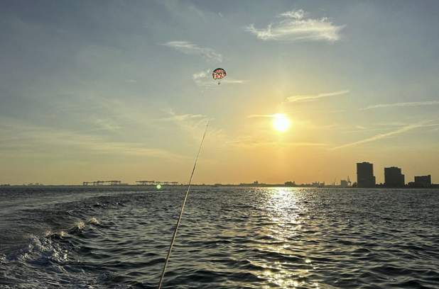 Sun going down over the Atlantic Ocean with people parasailing