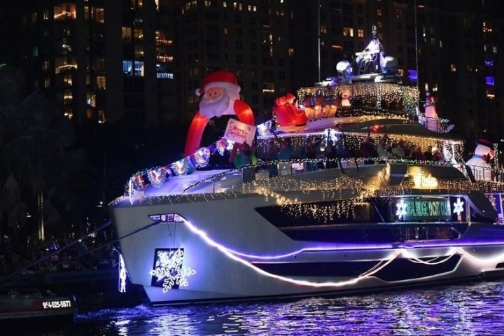 Yacht decorated with Christmas lights and inflatable Santa at night.