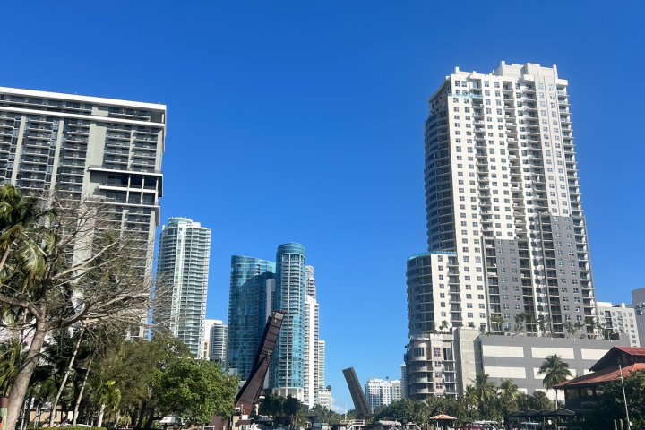 City skyline with high-rise buildings by river and open drawbridge under clear blue sky.