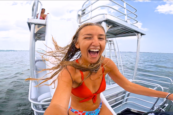 Woman in red bikini smiling on a boat slide over the water.