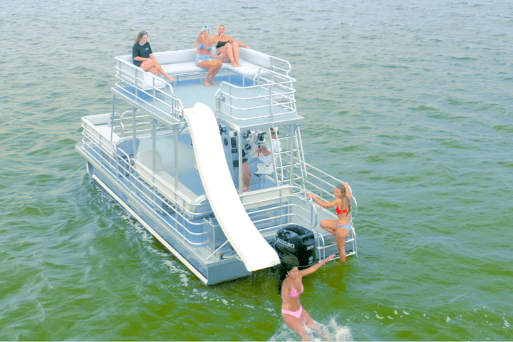 Pontoon boat with slide and people enjoying a sunny day on the water.