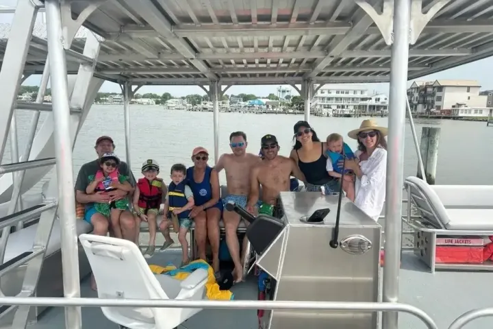 Group of people smiling on a boat in a marina setting.