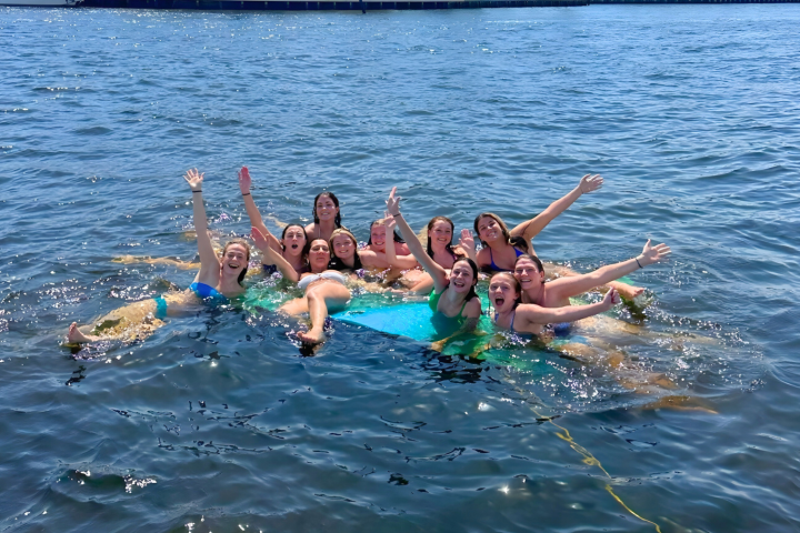 Group of people in swimsuits cheering while floating on water.