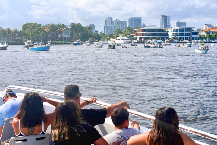 People on a boat in a city harbor, with multiple boats and buildings in the background.